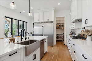 Kitchen featuring recessed lighting, a sink, white cabinetry, light wood-style floors, and stainless steel appliances