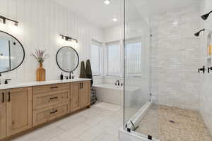 Bathroom featuring a euro shower, a soaking tub, double vanity, and a sink