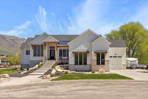 View of front of property featuring an attached garage, stone siding, and board and batten siding