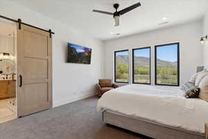 Bedroom with baseboards, carpet flooring, visible vents, and a barn door