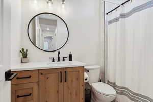 Full bath with toilet, curtained shower, and vanity
