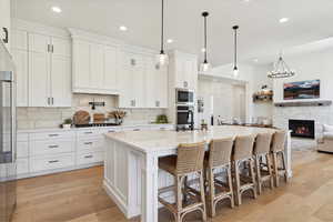 Kitchen with stainless steel microwave, a sink, white cabinetry, decorative backsplash, and light countertops