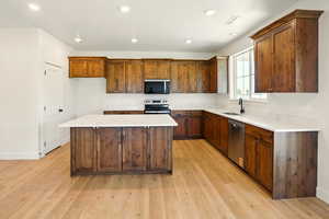 Kitchen featuring a sink, appliances with stainless steel finishes, recessed lighting, a center island, and light wood-style floors
