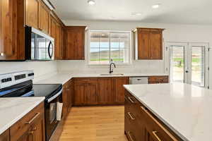 Kitchen featuring a healthy amount of sunlight, stainless steel appliances, light wood-type flooring, and a sink