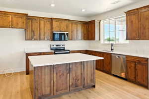 Kitchen with light wood-type flooring, stainless steel appliances, visible vents, and a sink