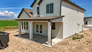 View of side of home featuring roof with shingles, a patio, and french doors