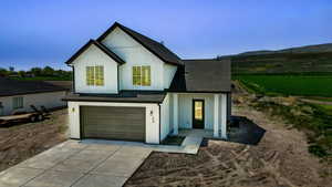 Modern farmhouse style home featuring driveway, roof with shingles, an attached garage, and a mountain view