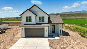 Modern inspired farmhouse with concrete driveway, a garage, a shingled roof, and a mountain view