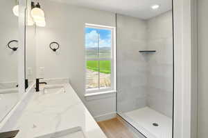Bathroom featuring vanity, baseboards, a tile shower, and wood finished floors