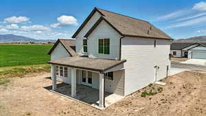 Rear view of house featuring a shingled roof, a mountain view, and a patio
