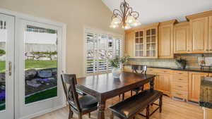Dining room with light wood finished floors, an inviting chandelier, visible vents, and lofted ceiling