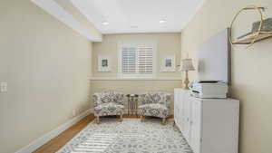 Sitting room featuring visible vents, wood finished floors, baseboards, and a wall unit AC