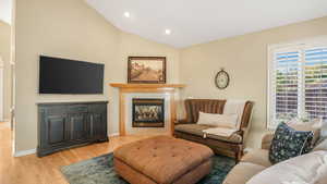 Living area with recessed lighting, baseboards, a multi sided fireplace, vaulted ceiling, and wood finished floors