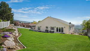 Rear view of house with a fenced backyard, stucco siding, a mountain view, and a lawn