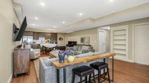 Living room with light wood finished floors, built in features, baseboards, and recessed lighting