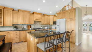 Kitchen with stainless steel microwave, a sink, white fridge with ice dispenser, and light wood-style floors