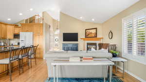 Living area with recessed lighting, light wood-type flooring, baseboards, and a glass covered fireplace