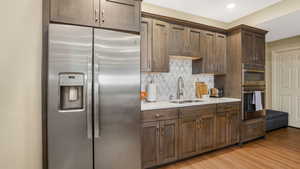 Kitchen featuring a sink, stainless steel appliances, tasteful backsplash, light countertops, and light wood-style floors
