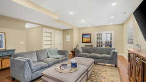 Living room featuring french doors, wood finished floors, built in features, baseboards, and recessed lighting