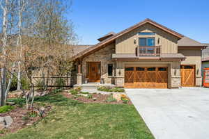 Craftsman inspired home with a front yard, a garage, a shingled roof, concrete driveway, and stone siding