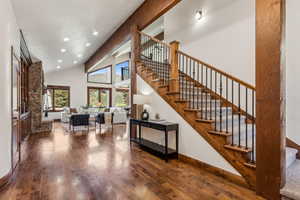 Stairway featuring baseboards, recessed lighting, wood-type flooring, and high vaulted ceiling