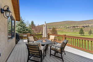 Deck with a yard, a fire pit, a mountain view, and golf course view