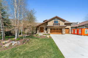 Craftsman-style home featuring concrete driveway, a garage, a front yard, and stone siding