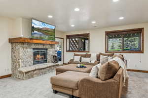 Carpeted living area featuring baseboards, a fireplace, and recessed lighting
