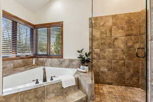 Full bathroom with a shower stall, lofted ceiling, and a bath