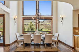 Dining area with a notable chandelier, a towering ceiling, and wood finished floors