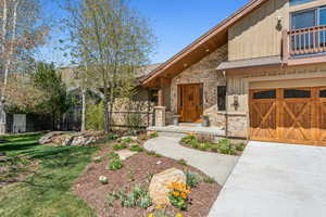 View of front of property with concrete driveway, stone siding, a front yard, and fence