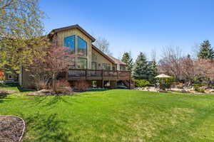 Rear view of house featuring a lawn, a patio area, stairway, and a wooden deck