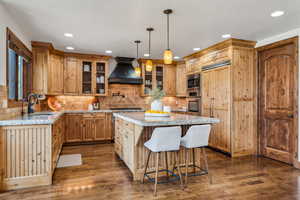 Kitchen with glass insert cabinets, a center island, a sink, stainless steel appliances, and custom exhaust hood