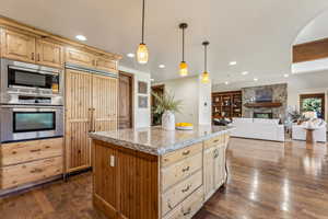 Kitchen featuring built in appliances, light brown cabinets, light stone counters, and recessed lighting