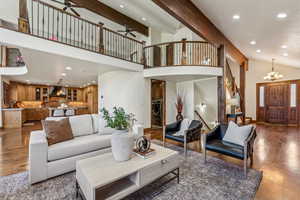 Living room featuring stairs, wood finished floors, ceiling fan with notable chandelier, and recessed lighting