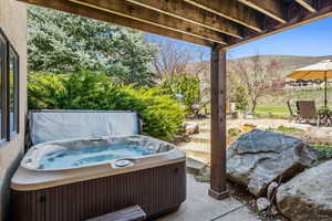 View of patio with a hot tub and a mountain view
