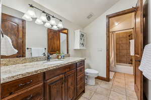 Full bathroom with baseboards, toilet, visible vents, tile patterned flooring, and vaulted ceiling