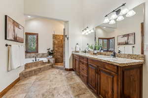 Bathroom featuring a healthy amount of sunlight, a garden tub, a sink, and double vanity
