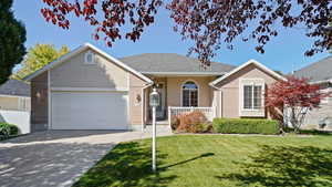 Ranch-style home featuring covered porch, driveway, a front yard, and a garage