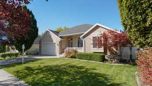 View of front of home featuring concrete driveway, fence, a front lawn, and a garage