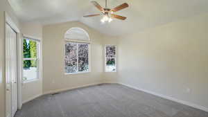 Unfurnished room featuring visible vents, lofted ceiling, baseboards, ceiling fan, and carpet flooring