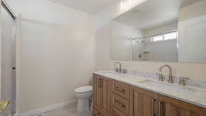 Bathroom with a sink, a shower with door, toilet, and visible vents