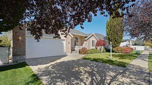 View of front facade with a garage, fence, a front yard, brick siding, and driveway