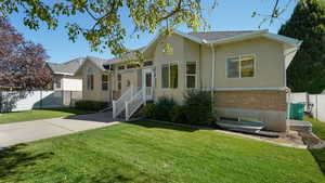 Ranch-style home with fence, stucco siding, brick siding, and a front yard
