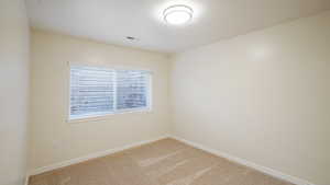 Carpeted spare room featuring baseboards and visible vents
