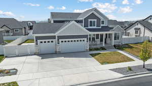 View of front of property with board and batten siding, covered porch, roof with shingles, a gate, and an attached garage