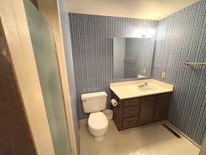Bathroom with vanity, wallpapered walls, toilet, and visible vents