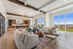 Living room featuring recessed lighting, an inviting chandelier, light wood-style flooring, and beam ceiling