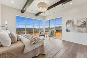 Bedroom with a mountain view, wood finished floors, visible vents, beamed ceiling, and baseboards