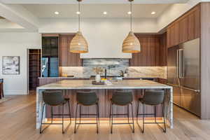 Kitchen with high end refrigerator, backsplash, modern cabinets, and brown cabinets